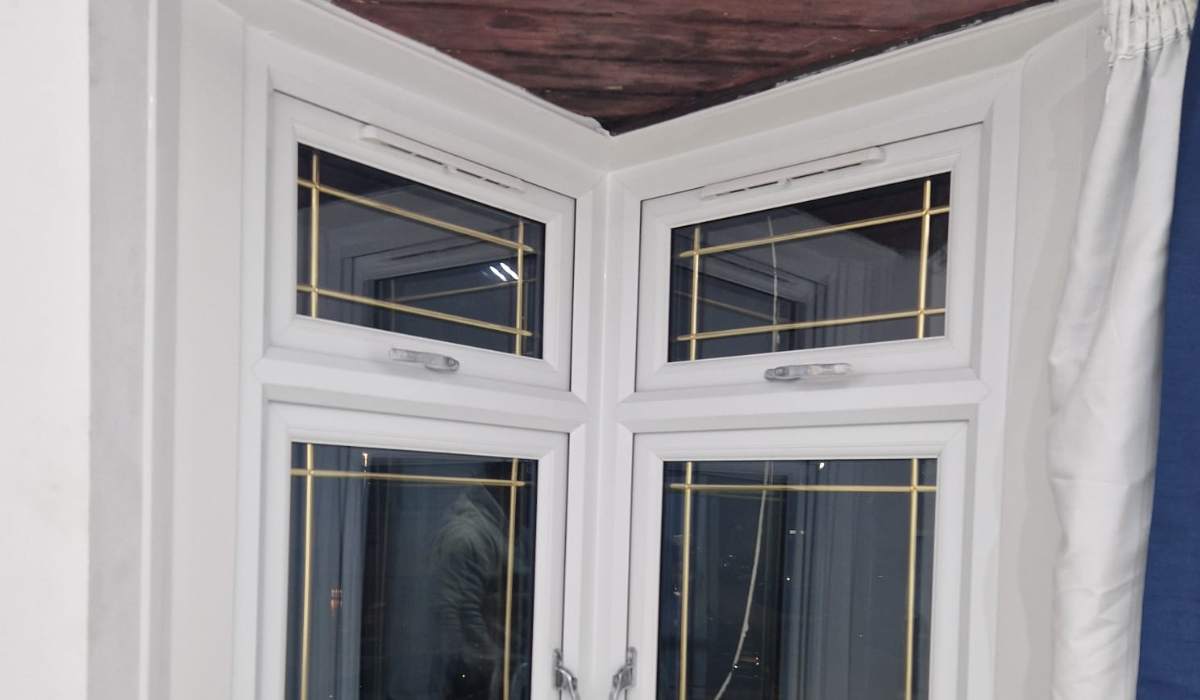 Interior view of white uPVC corner windows with top-opening vents and decorative glass - Redwood Shopfront